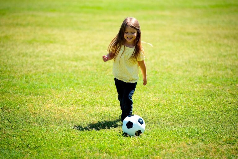 nina jugando con una pelota de futbol