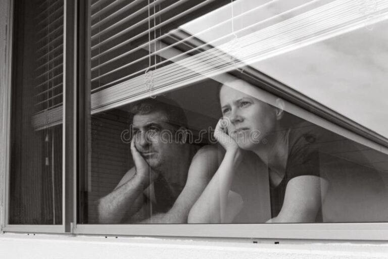 pareja mirando por una ventana triste